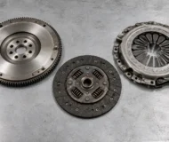 Illustration of a flywheel, clutch friction disc and diaphragm spring pressure plate on a workbench.